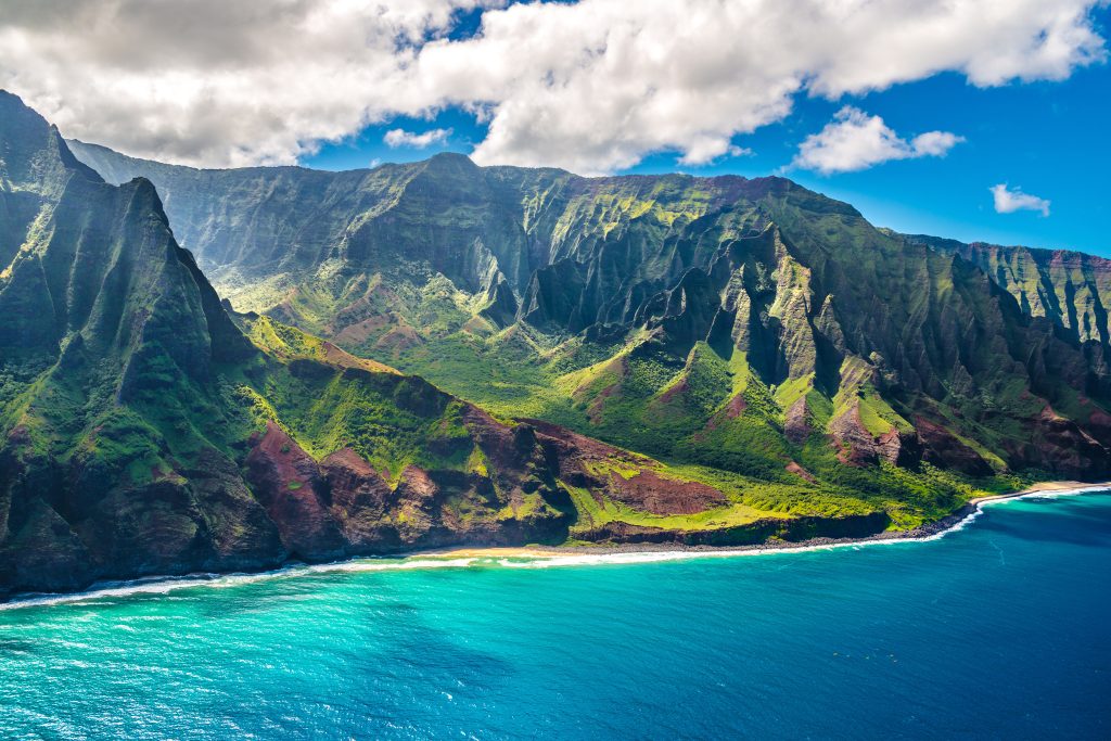 Mountain terrain for the Hawaiian islands with the bright blue water in front of the island.