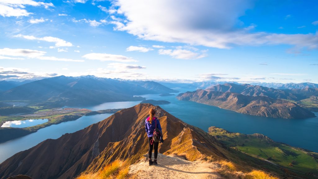 A hiker looking at the beautiful landscape of the mountains and Lake Wanaka. Roys Peak Track, South Island, New Zealand.